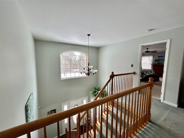 corridor featuring a notable chandelier, carpet floors, and a healthy amount of sunlight