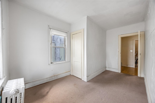 unfurnished bedroom featuring a closet, radiator heating unit, and carpet flooring