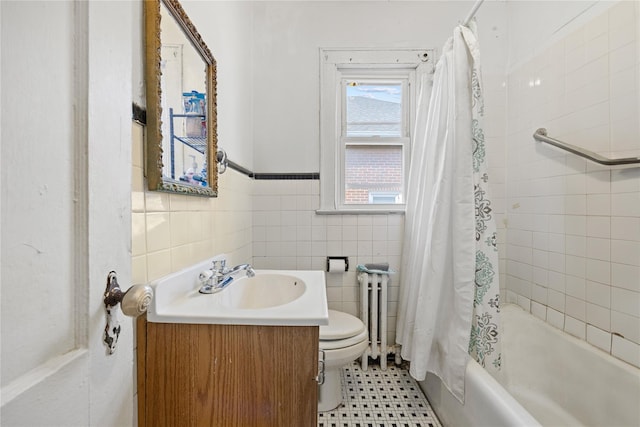 bathroom featuring toilet, vanity, radiator heating unit, shower / tub combo, and tile walls