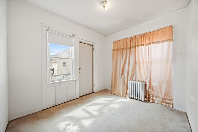 unfurnished room featuring radiator heating unit and carpet