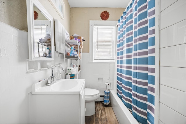 full bath featuring tile walls, a wainscoted wall, wood finished floors, toilet, and vanity