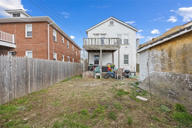 rear view of property with a balcony and fence