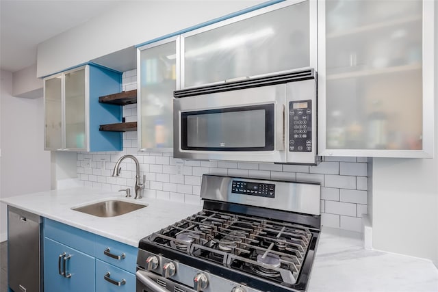 kitchen featuring sink, stainless steel appliances, tasteful backsplash, light stone countertops, and blue cabinets