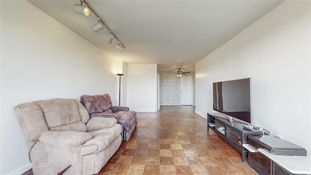 living area featuring a ceiling fan, baseboards, and track lighting