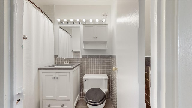 full bathroom featuring toilet, vanity, and tile walls