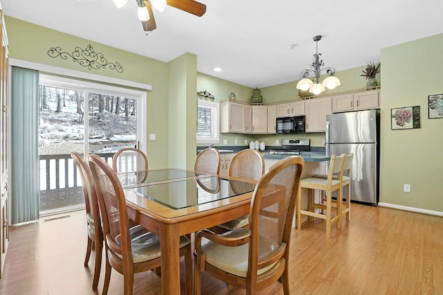 dining area with baseboards, ceiling fan with notable chandelier, visible vents, and light wood-style floors