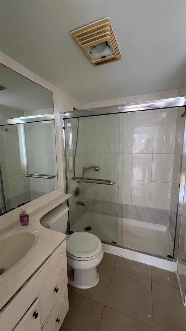 bathroom with tile patterned flooring, toilet, vanity, and walk in shower