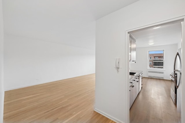 interior space with light wood-type flooring, radiator, and baseboards