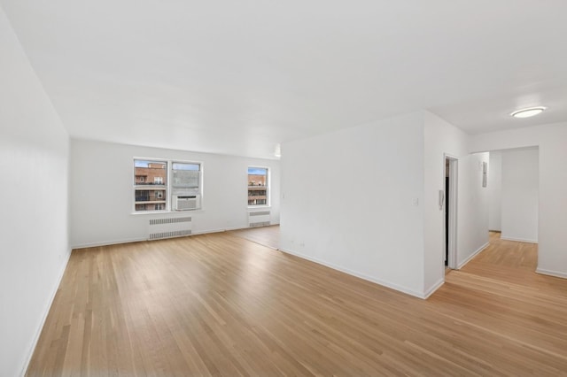 unfurnished living room featuring radiator, light wood-style flooring, and baseboards