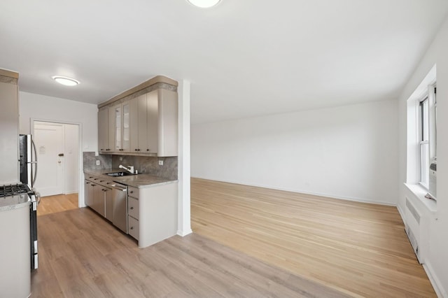 kitchen featuring a sink, light countertops, appliances with stainless steel finishes, tasteful backsplash, and glass insert cabinets