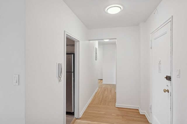 corridor with light wood-style floors and baseboards