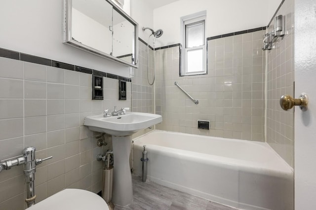 full bath with toilet, shower / bathing tub combination, wood finished floors, and tile walls