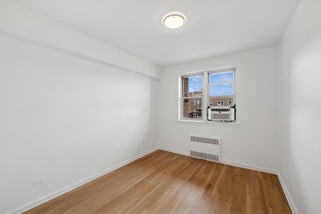 spare room with cooling unit, radiator, baseboards, and wood finished floors