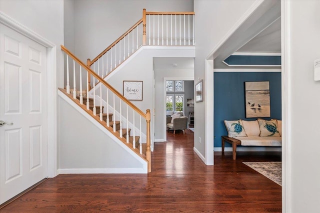 entrance foyer featuring a high ceiling, dark wood-style flooring, stairway, and baseboards