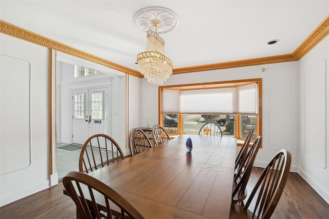 dining space with baseboards, dark wood finished floors, ornamental molding, an inviting chandelier, and french doors