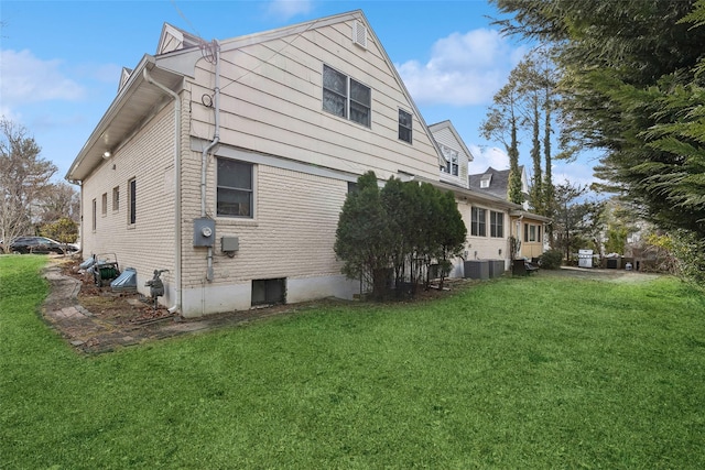 view of side of property with central AC unit and a yard