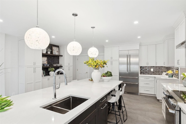 kitchen featuring pendant lighting, light countertops, appliances with stainless steel finishes, white cabinetry, and a sink