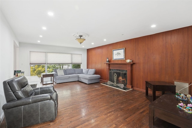 living room featuring recessed lighting, dark wood finished floors, wood walls, and a premium fireplace