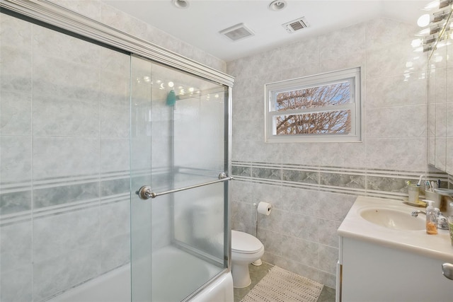 bathroom with shower / bath combination with glass door, tile walls, visible vents, toilet, and vanity