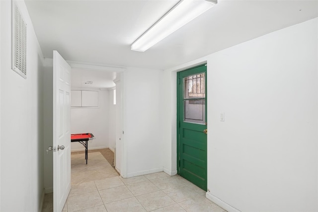 hallway with visible vents, baseboards, and light tile patterned floors