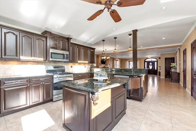 kitchen featuring stainless steel appliances, a kitchen island, dark brown cabinets, backsplash, and decorative light fixtures