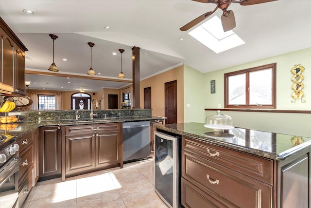 kitchen with wine cooler, a sink, appliances with stainless steel finishes, lofted ceiling with skylight, and decorative light fixtures