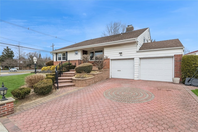 ranch-style house featuring a garage, decorative driveway, brick siding, and a chimney