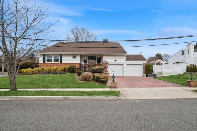 single story home featuring decorative driveway, brick siding, a chimney, a front yard, and fence