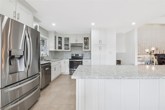 kitchen with under cabinet range hood, stainless steel appliances, a sink, white cabinetry, and decorative backsplash