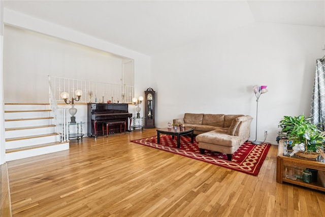 living area featuring stairs, vaulted ceiling, and wood finished floors