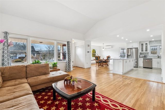 living room featuring lofted ceiling, light wood finished floors, a wall mounted AC, and recessed lighting