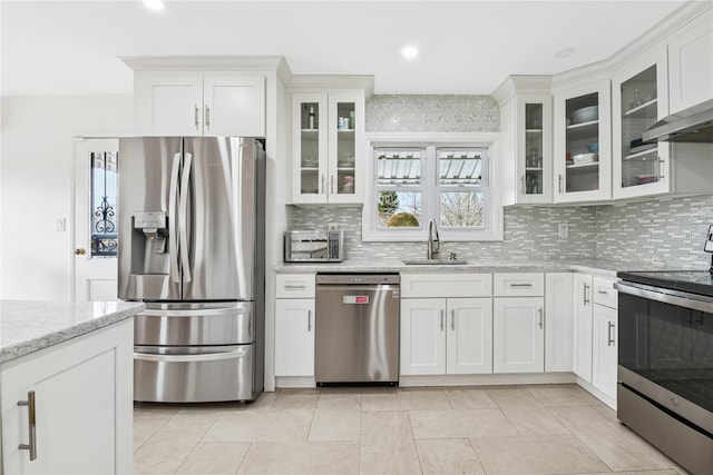 kitchen with light stone counters, appliances with stainless steel finishes, white cabinets, and a sink