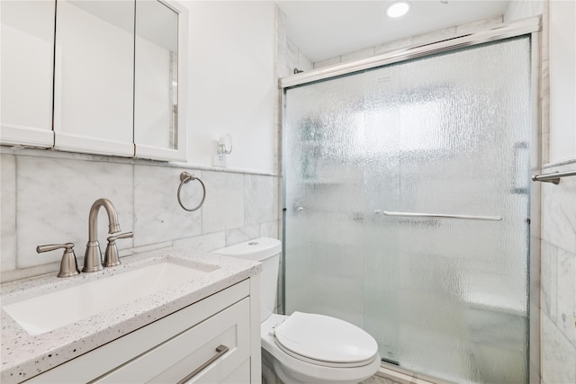 full bathroom featuring toilet, a stall shower, tile walls, and vanity