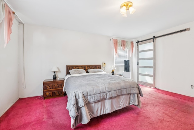 bedroom with a barn door, carpet, and baseboards