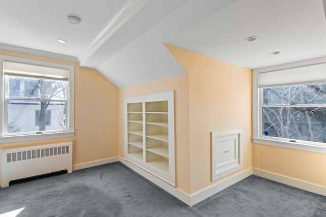 bonus room featuring built in features, dark colored carpet, and radiator