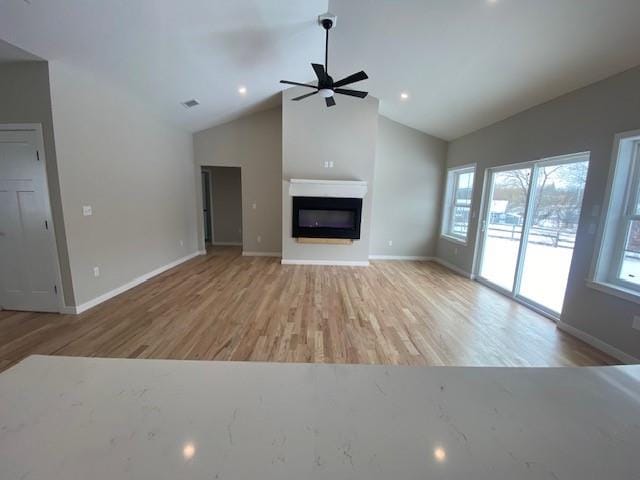 unfurnished living room with ceiling fan, high vaulted ceiling, and light hardwood / wood-style floors