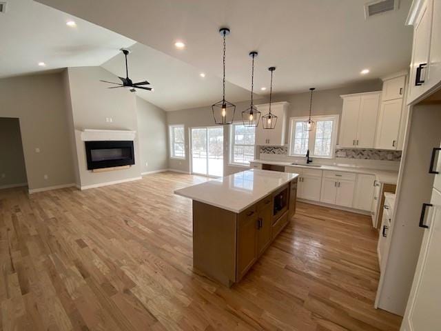 kitchen featuring ceiling fan, a center island, sink, and white cabinets