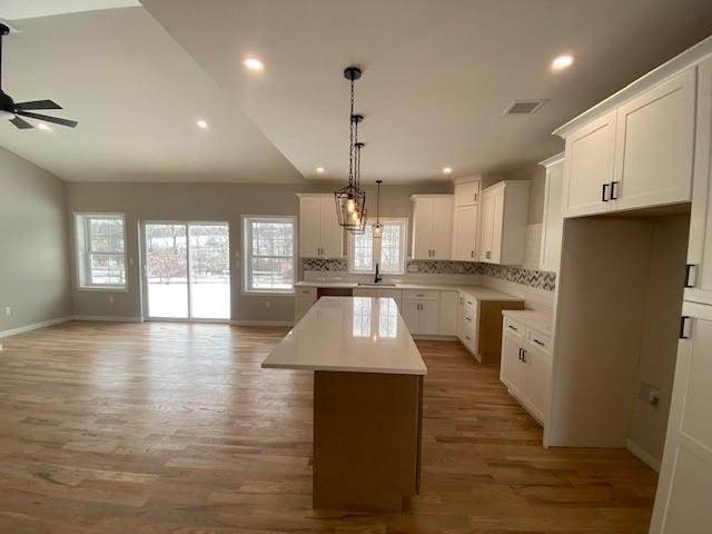 kitchen featuring backsplash, a center island, sink, and white cabinets