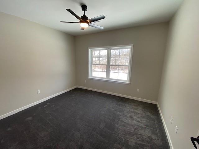 empty room with dark carpet and ceiling fan