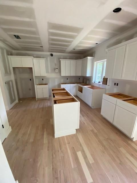 89 Leslie Rd, Newburgh, NY 12550 - kitchen featuring light wood finished floors, a kitchen island, white cabinetry, and beam ceiling