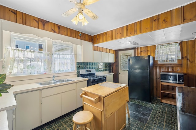 kitchen with freestanding refrigerator, light countertops, gas range, stainless steel microwave, and a sink