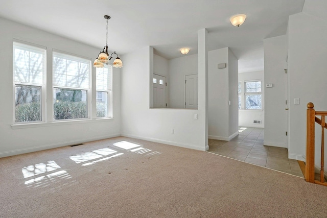 spare room with carpet floors, visible vents, a chandelier, tile patterned flooring, and baseboards