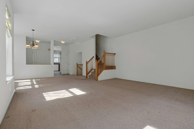 unfurnished living room with carpet, a notable chandelier, and stairway