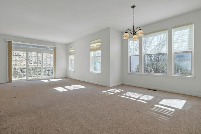 empty room featuring a healthy amount of sunlight, baseboards, visible vents, and a notable chandelier