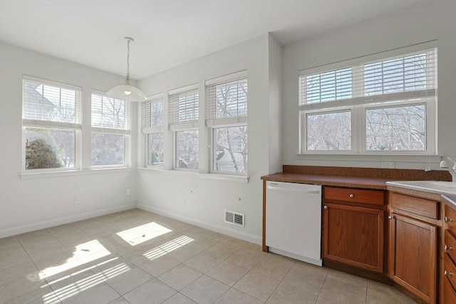 kitchen featuring plenty of natural light, visible vents, dishwasher, brown cabinets, and a sink