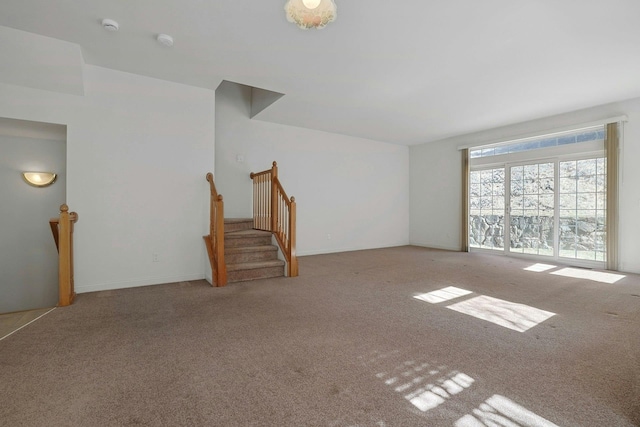 carpeted empty room featuring stairway