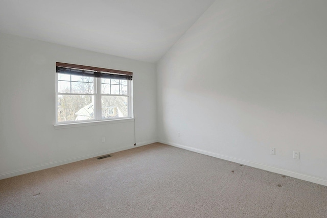 empty room with lofted ceiling, light carpet, visible vents, and baseboards