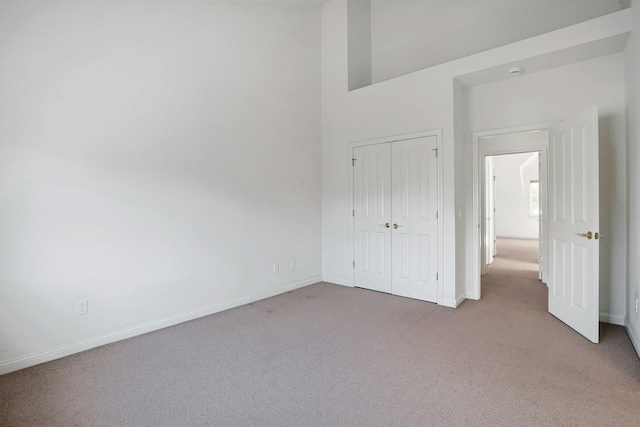 unfurnished bedroom with baseboards, a closet, and light colored carpet