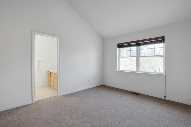 unfurnished room with light colored carpet, vaulted ceiling, visible vents, and baseboards