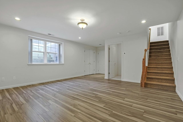 unfurnished living room featuring light wood-type flooring, stairway, visible vents, and recessed lighting